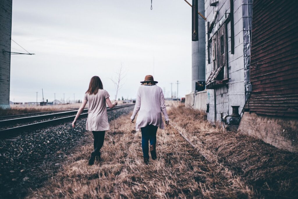 photo of two persons walking along railway