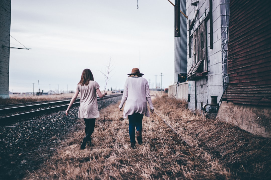 photo of two persons walking along railway