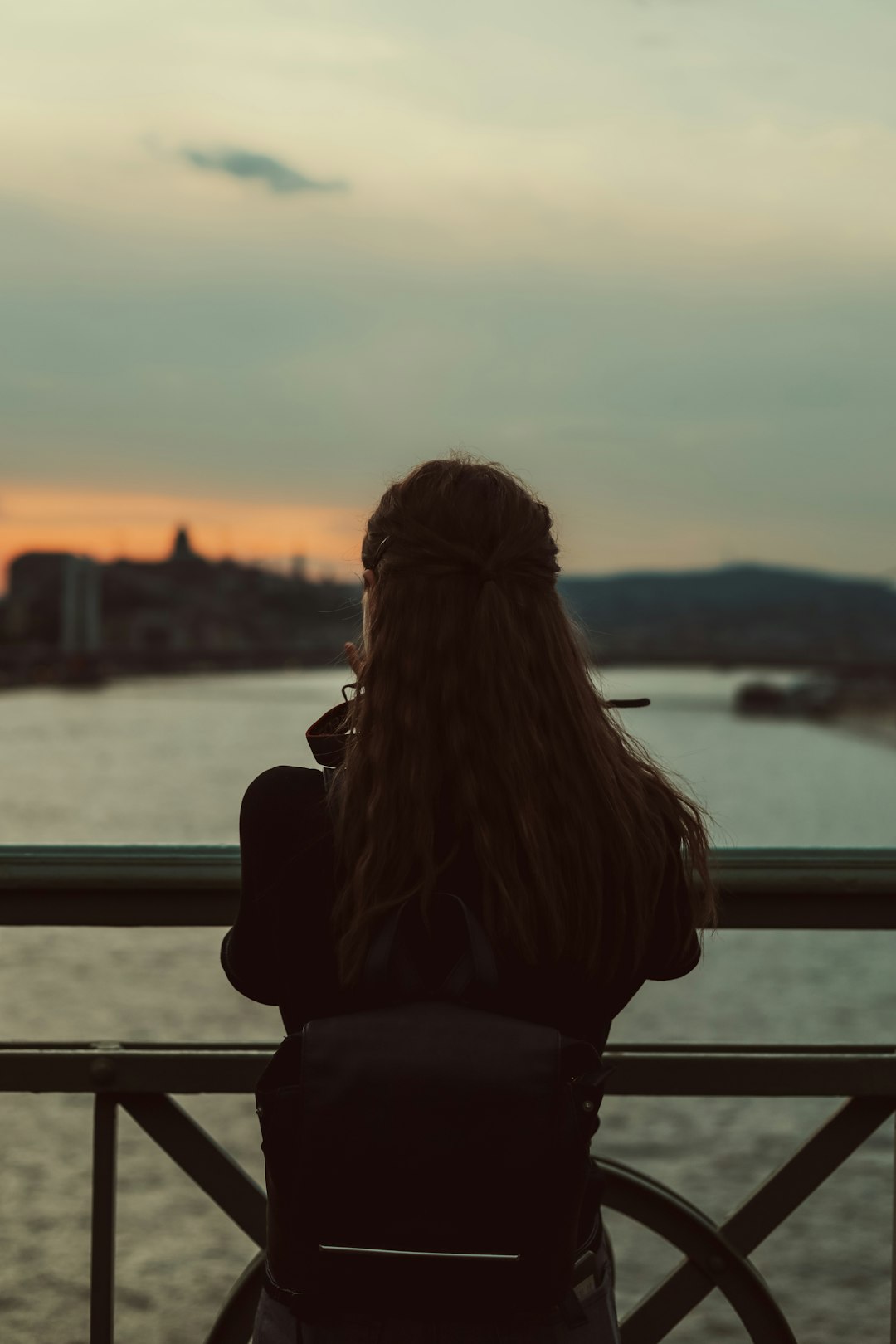 a woman sitting on a bench looking at the water
