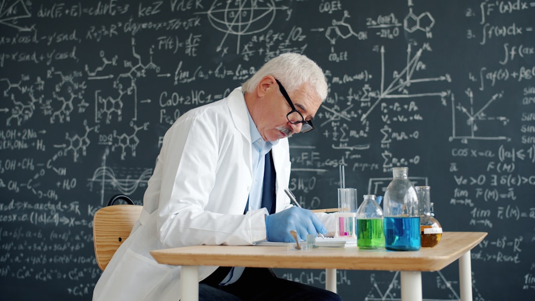 Scientist in lab coat working at desk with formulas.