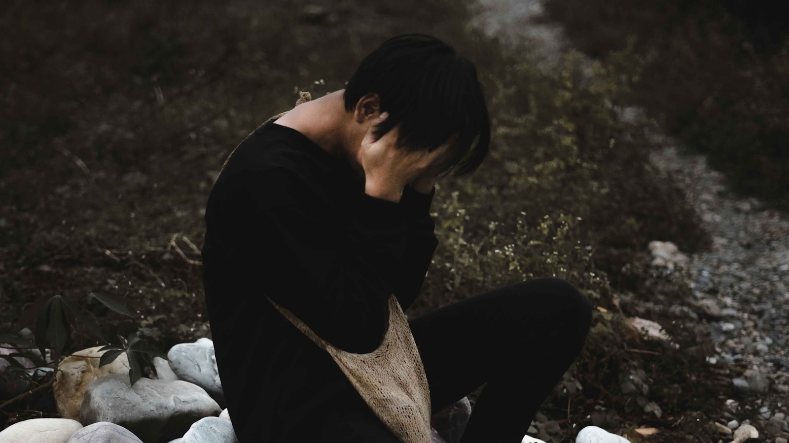 man in black shirt and gray pants sitting on ground